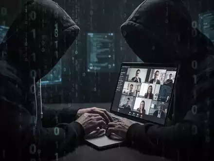 Verschwommene Gestalt in Kapuzenjacke tippt auf Laptop, im Hintergrund Binärcode und Videokonferenz-Bildschirm. - Foto: über boerse-global.de
