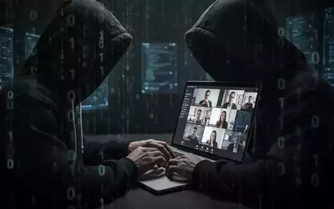 Verschwommene Gestalt in Kapuzenjacke tippt auf Laptop, im Hintergrund Binärcode und Videokonferenz-Bildschirm. - Foto: über boerse-global.de