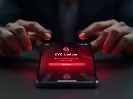 Ein Smartphone-Bildschirm zeigt eine gefĂ€lschte 'KYC-Update'-Benachrichtigung, mit unscharfen HĂ€nden im Hintergrund, was auf Cyberbetrug hinweist. - Foto: ĂŒber boerse-global.de