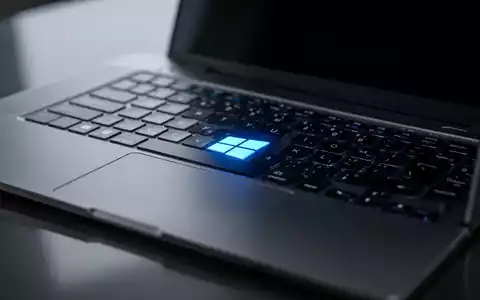 Nahaufnahme einer Laptop-Tastatur mit leuchtend blauem Windows-Logo auf der Windows-Taste, das sich auf einer dunklen Oberfläche spiegelt. - Foto: über boerse-global.de