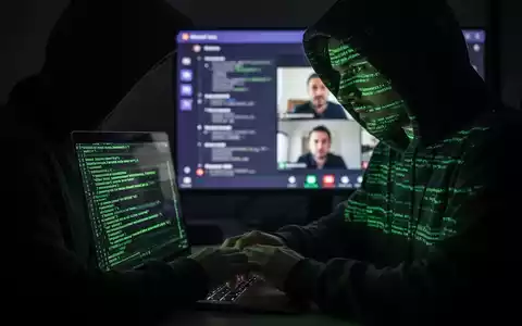 Verschwommene Gestalt in Kapuzenjacke tippt auf Laptop, im Hintergrund unscharfer Microsoft-Teams-Anruf, symbolisiert Vishing-Angriff. - Foto: über boerse-global.de