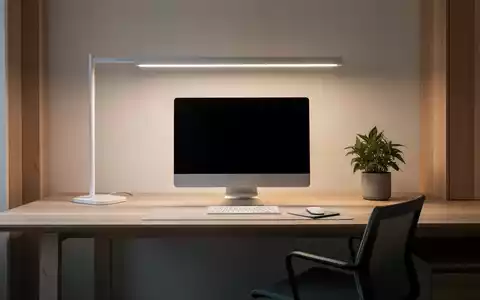 Ein minimalistischer Schreibtisch mit einem Monitor, einer kleinen Pflanze und natürlicher Beleuchtung, die eine ruhige Arbeitsatmosphäre schafft. - Foto: über boerse-global.de