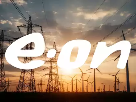Silhouetten von Hochspannungsleitungen und Windturbinen vor einem dramatischen Himmel mit warmem Licht, das Investitionen in Energienetze symbolisiert. - Foto: über boerse-global.de