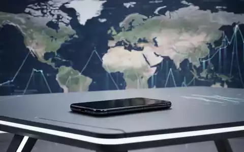 Schlankes, markenloses Smartphone auf futuristischem Tisch, verschwimmende Karte Europas und Nordamerikas im Hintergrund. - Foto: über boerse-global.de