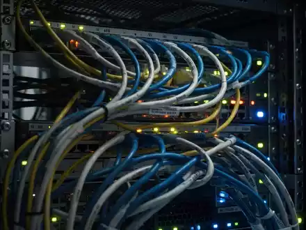 Nahaufnahme von leuchtenden Netzwerkkabeln und Serverlichtern in einem Rechenzentrumsrack, die komplexe Technologieinfrastruktur darstellen. - Foto: über boerse-global.de