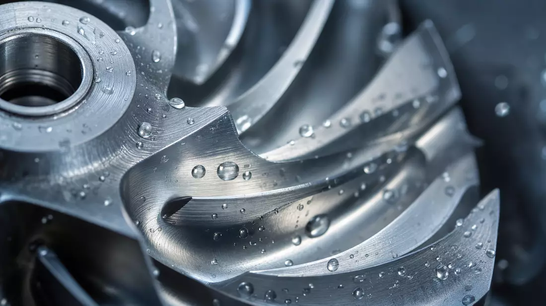 Makroaufnahme eines nassen Edelstahl-Pumpenlaufrads mit Wassertropfen