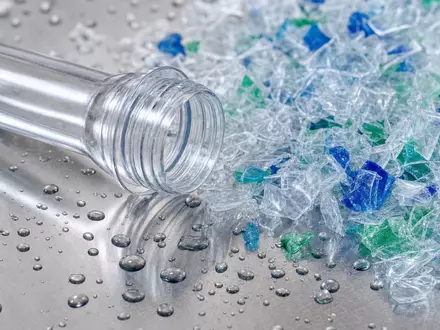 Makroaufnahme illustriert Krones AG DE0006335003 durch Nahaufnahme von PET-Kunststoff-Preform und farbigen Recycling-Flakes auf glänzender Edelstahloberfläche - Foto: THN