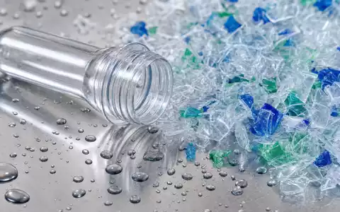 Makroaufnahme illustriert Krones AG DE0006335003 durch Nahaufnahme von PET-Kunststoff-Preform und farbigen Recycling-Flakes auf glänzender Edelstahloberfläche - Foto: THN