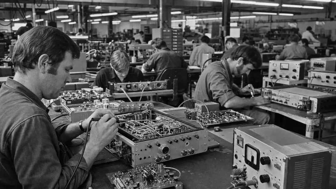Schwarzweiß-Dokumentarfoto von Technikern bei der Montage von Funkgeräten in einer Fabrik