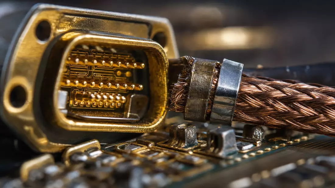 Extreme Nahaufnahme eines goldenen Steckverbinders mit Kupfergeflecht-Kabel und Platine