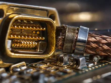 Makroaufnahme zeigt vergoldeten Steckverbinder und Kupfergeflecht als Materialdetail für L3Harris Technologies, ISIN US5024311095, scharf fokussiert - Foto: THN
