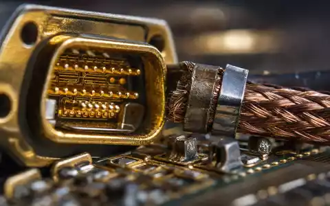 Makroaufnahme zeigt vergoldeten Steckverbinder und Kupfergeflecht als Materialdetail für L3Harris Technologies, ISIN US5024311095, scharf fokussiert - Foto: THN