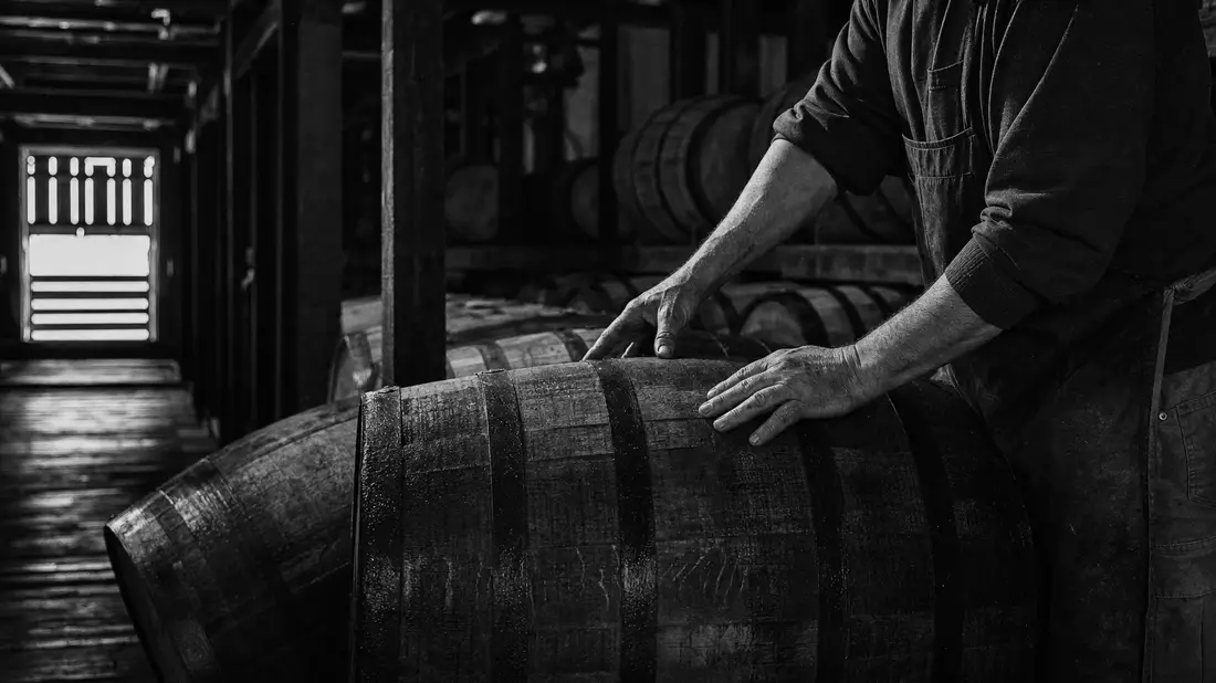 Schwarzweiß-Reportage eines Küfers beim Rollen eines Bourbonfasses in Kentucky