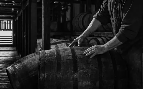 Brown-Forman Corp. US1170431092 dokumentarisch: Handwerker rollt schweres Bourbon-Eichenfass im Kentucky-Rickhouse in Schwarzweiß-Reportage - Foto: THN