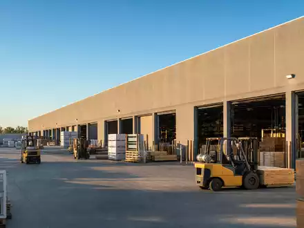 Builders FirstSource US12189T1043 großes Baustoff-Distributionszentrum in Irving Texas mit Gabelstaplern und Holzpaletten draußen - Foto: THN