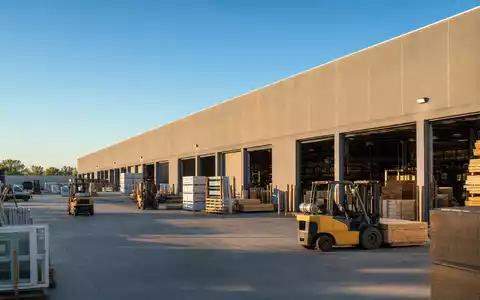 Builders FirstSource US12189T1043 großes Baustoff-Distributionszentrum in Irving Texas mit Gabelstaplern und Holzpaletten draußen - Foto: THN