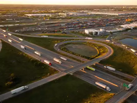 C.H. Robinson Worldwide US12468P1049 zeigt Autobahn-Kreuz mit zahlreichen Frachtlastwagen bei goldenem Sonnenuntergang über der Landschaft - Foto: THN
