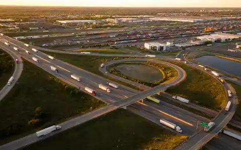 C.H. Robinson Worldwide US12468P1049 zeigt Autobahn-Kreuz mit zahlreichen Frachtlastwagen bei goldenem Sonnenuntergang über der Landschaft - Foto: THN