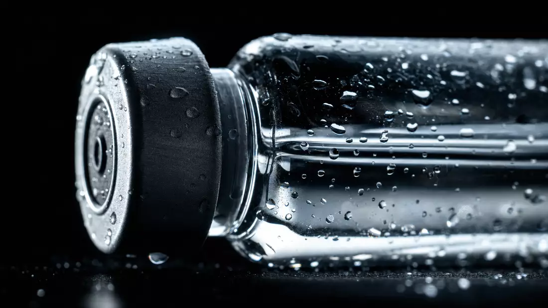 Extreme Makroaufnahme einer Glasampulle mit Wassertropfen und Metallverschluss