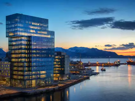 DNB Bank ASA (ISIN NO0010161896) symbolisiert durch modernen Glasturm am Hafen einer nordischen Stadt - Foto: THN