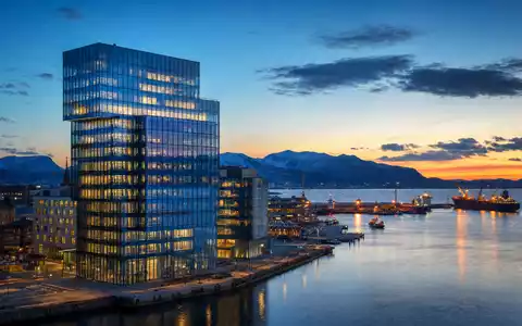 DNB Bank ASA (ISIN NO0010161896) symbolisiert durch modernen Glasturm am Hafen einer nordischen Stadt - Foto: THN