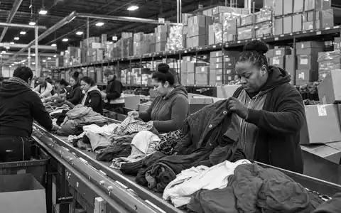 Next plc (GB0032089863): dokumentarische Schwarzweiß-Reportage aus einem großen Bekleidungs-Logistikzentrum mit fleißigen Mitarbeitern bei der Arbeit - Foto: THN