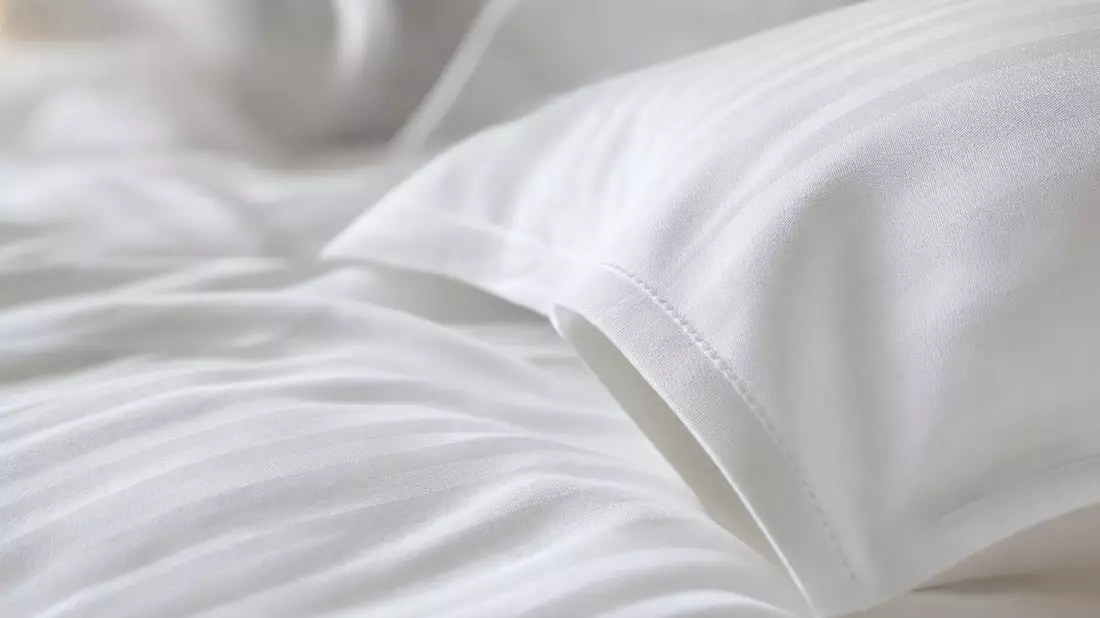 Makroaufnahme von weißer, edler Hotelbettwäsche mit feiner Stoffstruktur