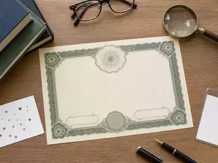 Informa plc (ISIN GB00BMJ6DW54) illustriert ein Flatlay-Arrangement mit Aktienzertifikat, Fachbüchern und Verlags-Utensilien - Foto: THN