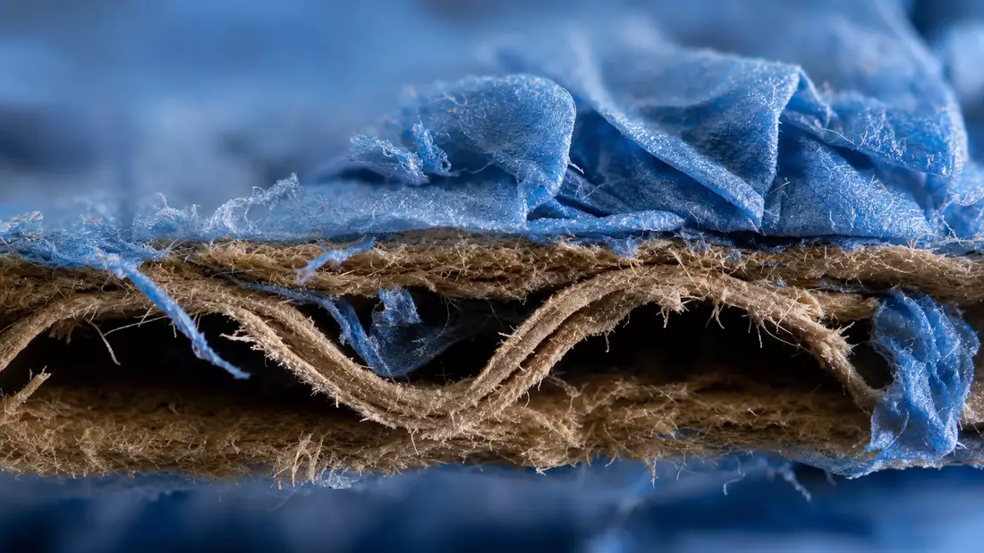 Makroaufnahme von Wellpappentextur und blauem Handschuhmaterial in Nahaufnahme