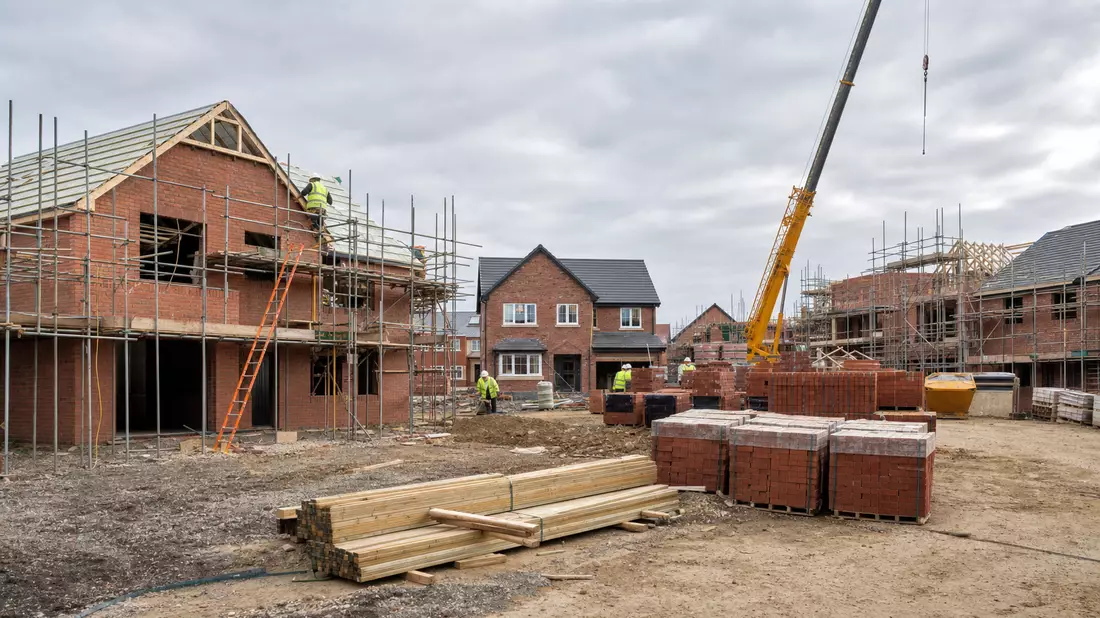 Baustelle mit Ziegelhäusern, Gerüst und Kran auf englischer Wohnsiedlung