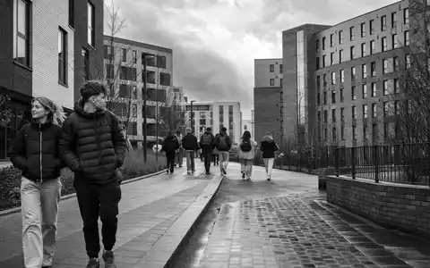 The Unite Group plc GB0033872168 dokumentiert schwarzweiß Studierende zwischen Wohnblöcken einer britischen Universitätsstadt im Alltag - Foto: THN
