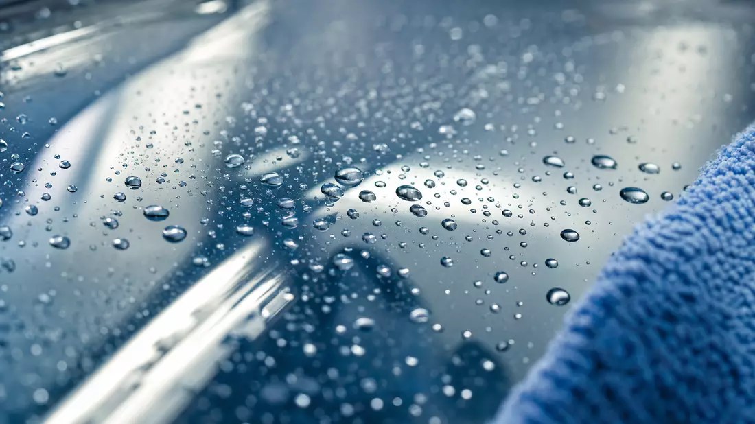 Makroaufnahme von Wassertropfen auf glänzender Glasoberfläche