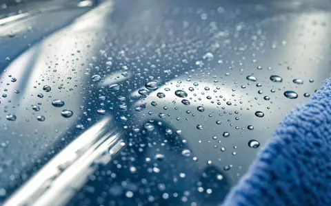 ISS A/S (DK0010181304) zeigt Makroaufnahme von Wassertropfen auf gereinigter Glasfläche mit Mikrofasertuch am Bildrand - Foto: THN