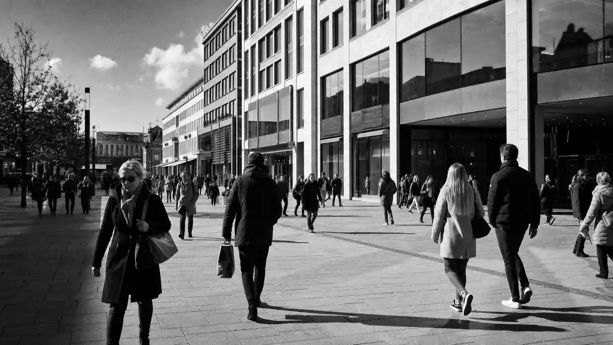 Dokumentarisches Schwarzweißfoto einer belebten deutschen Einkaufsstraße mit Gewerbefassaden