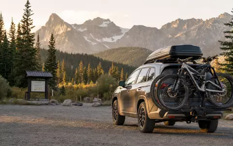 Thule Group AB SE0007158910 zeigt ein SUV mit Dachbox und Fahrradträgern vor Bergkulisse - Foto: THN
