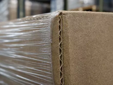 Prologis Inc. Branche mit ISIN US74340W1036 gezeigt durch Makroaufnahme von Wellpappe und Stretchfolie auf Palette - Foto: THN