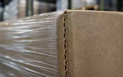 Prologis Inc. Branche mit ISIN US74340W1036 gezeigt durch Makroaufnahme von Wellpappe und Stretchfolie auf Palette - Foto: THN
