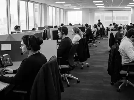 Progressive Corp US7433151039 illustriert Schwarzweiß-Reportage eines belebten Callcenters mit vielen telefonierenden Versicherungsagenten an Schreibtischen - Foto: THN