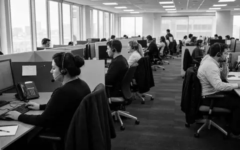 Progressive Corp US7433151039 illustriert Schwarzweiß-Reportage eines belebten Callcenters mit vielen telefonierenden Versicherungsagenten an Schreibtischen - Foto: THN
