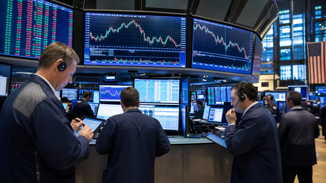 Editorial-Foto von Börsenhändlern vor großen Bildschirmen mit Aktiencharts am Trading-Floor