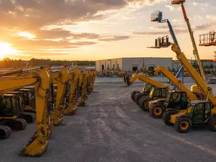United Rentals Inc. (US9113631090) betreibt riesige Vermietungsplätze mit unbedruckten gelben Baggern und Hebebühnen bei Sonnenuntergang - Foto: THN