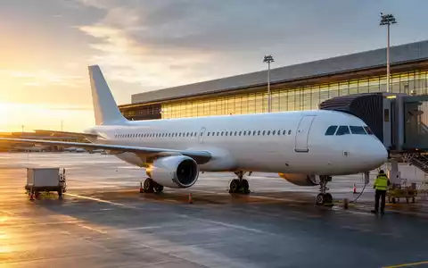 United Airlines (ISIN US9100471096): unbedrucktes weißes Passagierflugzeug am Gate im goldenen Abendlicht fotorealistisch dargestellt - Foto: THN