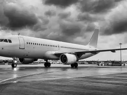 United Airlines (ISIN US9100471096): dokumentarische Schwarzweiß-Aufnahme eines unbedruckten Passagierjets auf regennasser Rollbahn unter dramatischem Himmel - Foto: THN