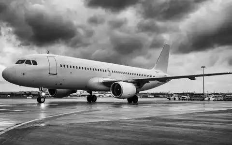 United Airlines (ISIN US9100471096): dokumentarische Schwarzweiß-Aufnahme eines unbedruckten Passagierjets auf regennasser Rollbahn unter dramatischem Himmel - Foto: THN