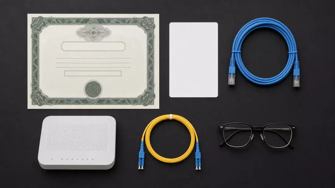 Flatlay mit Aktienzertifikat, ISIN-Karte, Router und Netzwerkkabeln