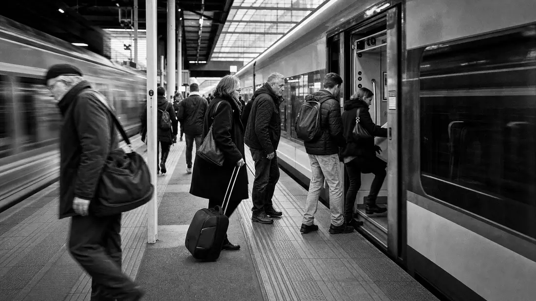 Schwarzweiß-Dokumentarfoto von Passagieren beim Einstieg in einen Zug