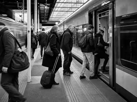 Schwarzweiß-Reportage vom Bahnsteig zeigt Pendleralltag, passend zu Trainline plc, ISIN GB00B4Z5Y988, im Reiseticketing-Sektor - Foto: THN