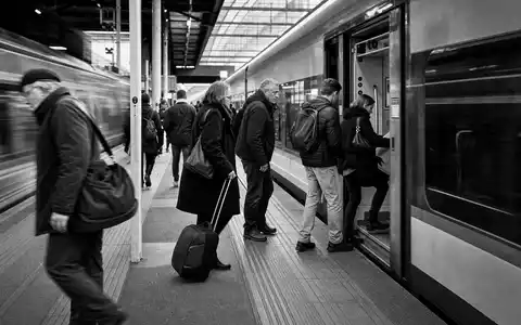 Schwarzweiß-Reportage vom Bahnsteig zeigt Pendleralltag, passend zu Trainline plc, ISIN GB00B4Z5Y988, im Reiseticketing-Sektor - Foto: THN
