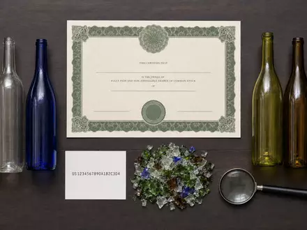 Verallia SA (ISIN FR0013506730) symbolisiert dieses Flatlay mit Aktienzertifikat, ISIN-Karte und farbigen recycelten Glasflaschen - Foto: THN