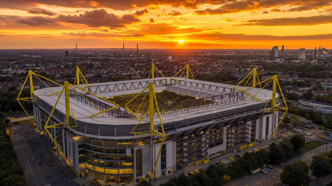 Luftaufnahme eines gelb-schwarzen Fußballstadions im Ruhrgebiet bei Sonnenuntergang